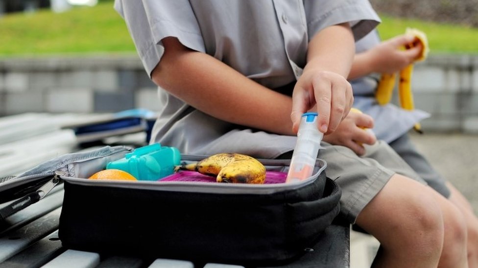 Мальчик с упакованным ланчем достает свой автоинжектор для лечения анафилаксии