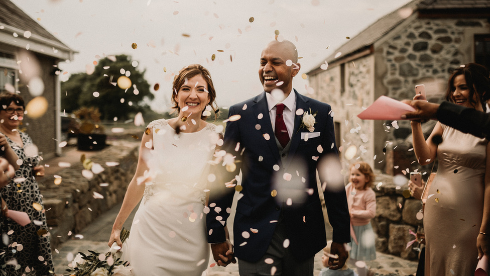 A picture of a wedding couple with confetti falling in front of them