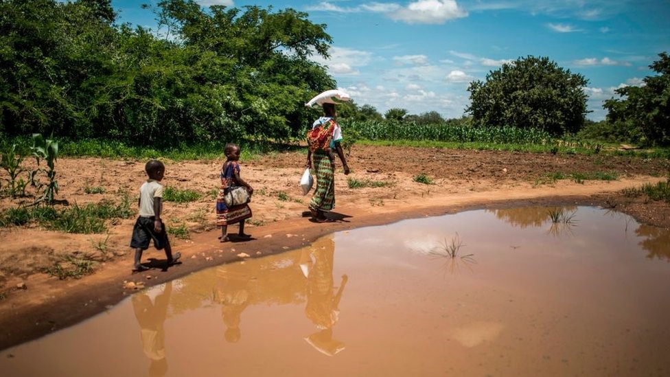 A mother and her children walk back home after collecting food from a distribution organised by the World Food Programme (WFP) in Simumbwe, Zambia, on January 22, 2020