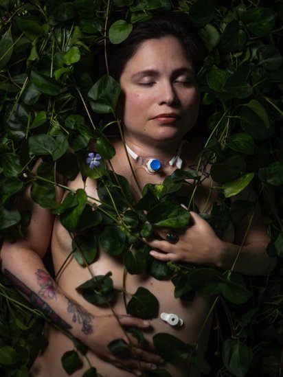 Ana Estrada rodeada de hojas verdes