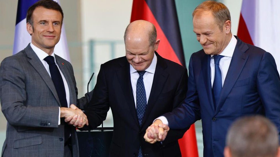 (L-R) French President Emmanuel Macron, German Chancellor Olaf Scholz and Poland's Prime Minister Donald Tusk shake hands after a news conference at the Chancellery in Berlin