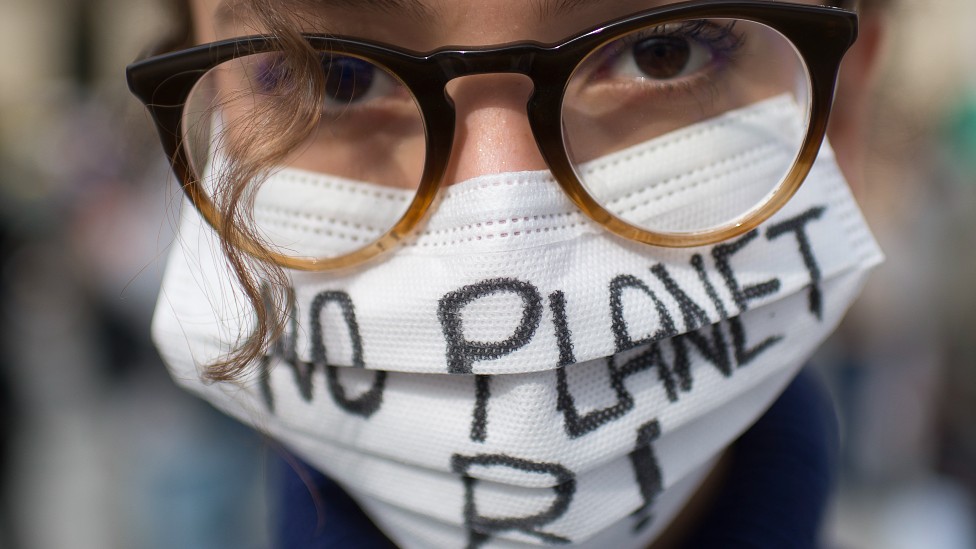 Una joven con una mascarilla que dice "no hay planeta B"