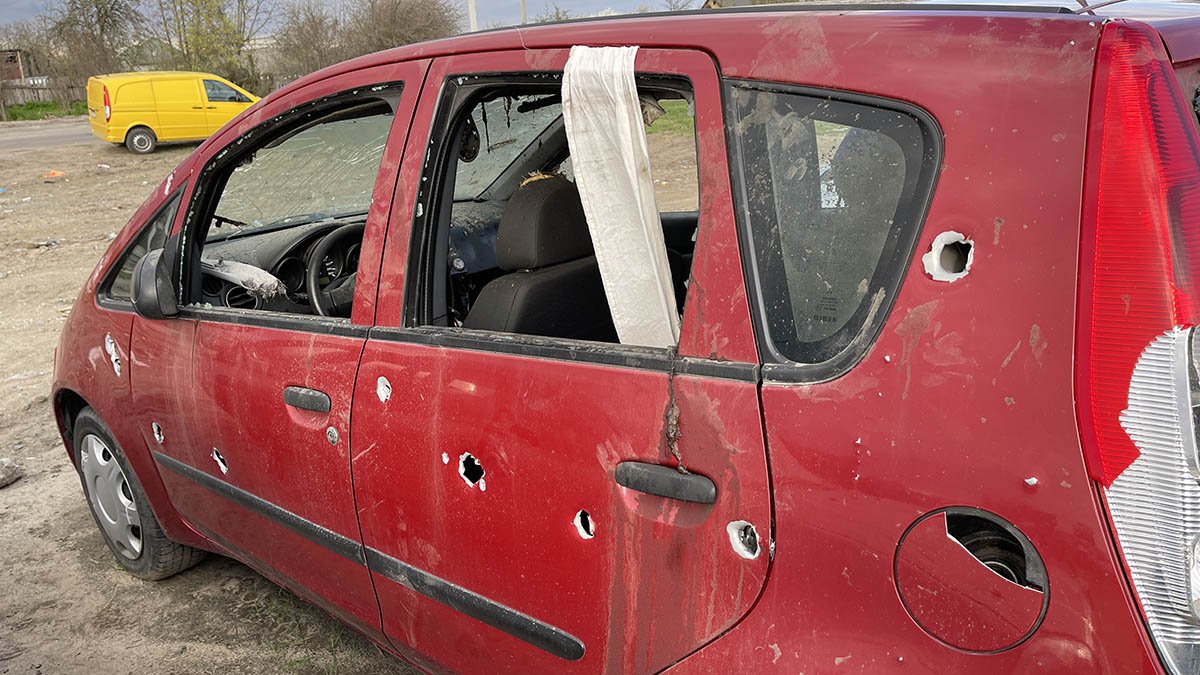 Carro com bandeira branca e buracos de bala