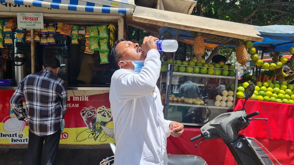 A man drinks water on a hot afternoon in Mumbai city