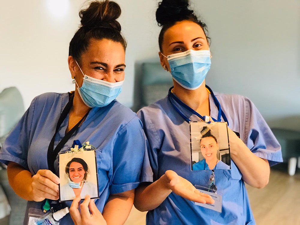Two nurses in masks, holding self-portraits