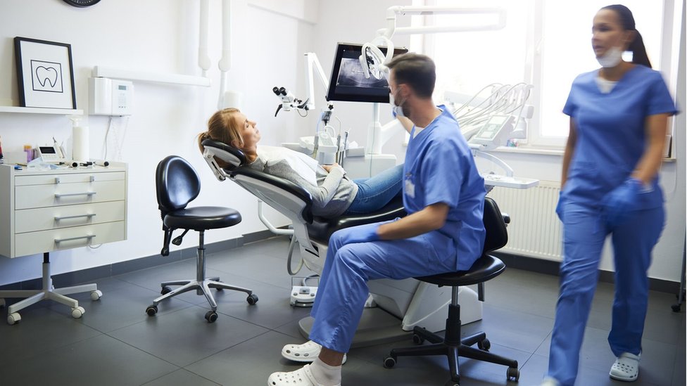 A dentist and dental nurse attend a patient