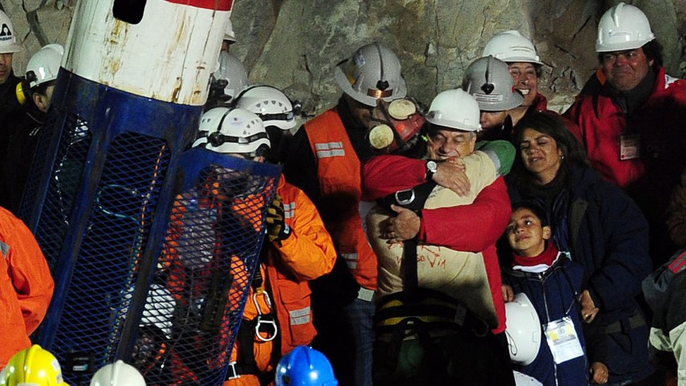 Cápsula de rescate y mineros siendo rescatados de la mina donde estaban atrapados en Copiapó, Chile, junto al entonces presidente Sebastián Piñera.