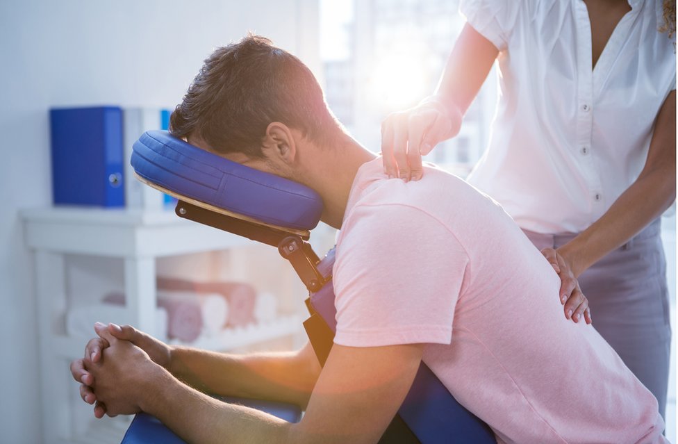 Las cuclillas y las sentadillas ayudan a un rango mayor de movimiento en las caderas, lo que ayuda a quitar presión al cuello y la espalda. Hombre recibiendo fisioterapia.