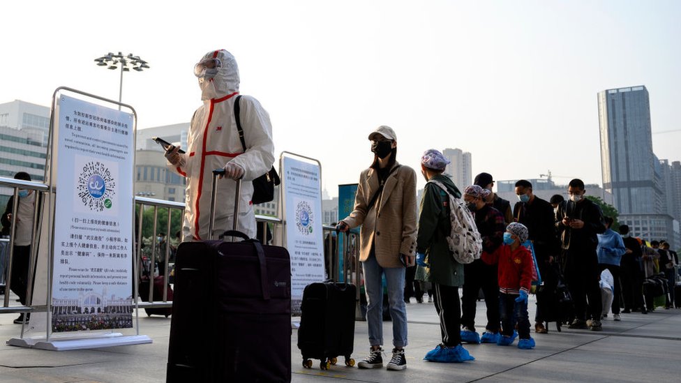 Hankou Tren İstasyonu'nun önünde bekleyen bazı yolcular tüm vücutlarını koruyucu kıyafetler giyerken, bazıları sadece yüz maskesi taktı.