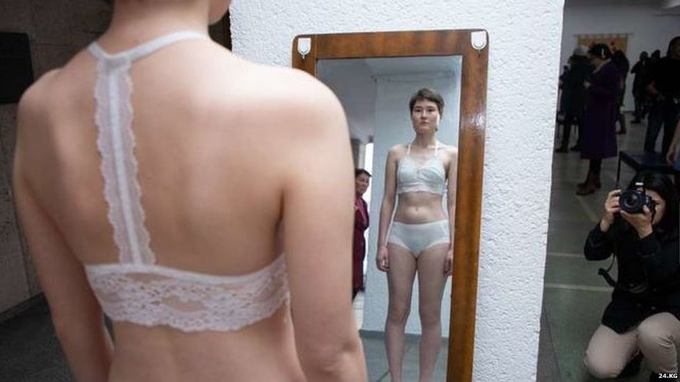 Женщина в нижнем белье смотрит в зеркало