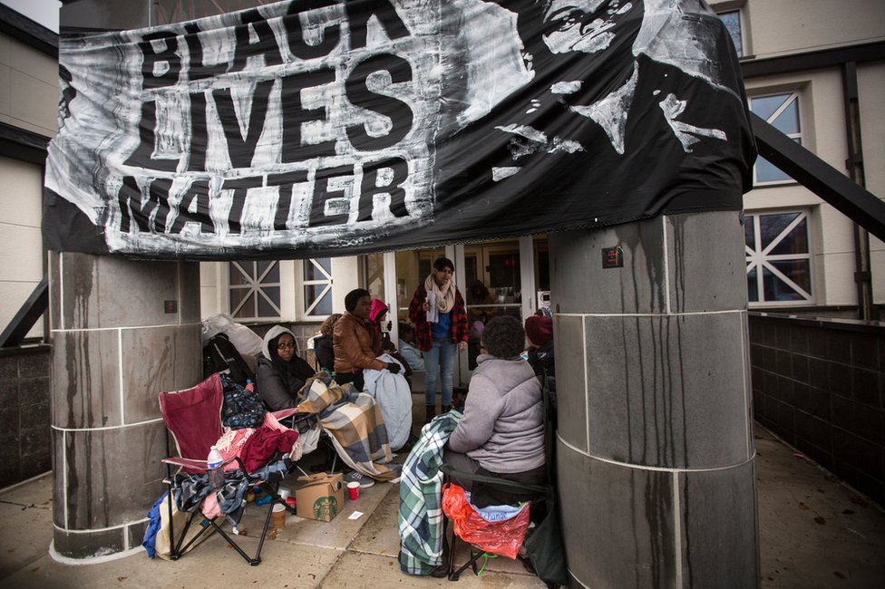 Лагерь протестующих возле полицейского участка под транспарантом с надписью «Black Lives Matter»
