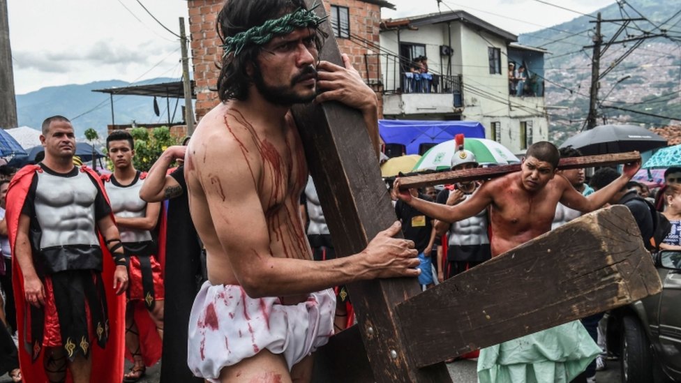 Hombre que interpreta a Jesús carga la cruz.