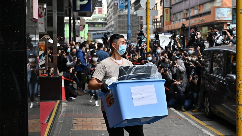 2021/12/29: A police officer carries news material and evidence in a blue plastic box after searching the office of Stand News. Amid the political suppression, Hong Kong independent news outlet was raided and searched by 200 police officers.