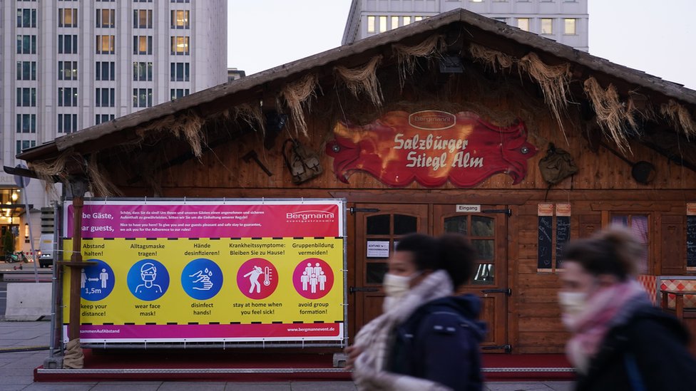 People wearing protective face masks walk past Christmas market stalls at Potsdamer Platz