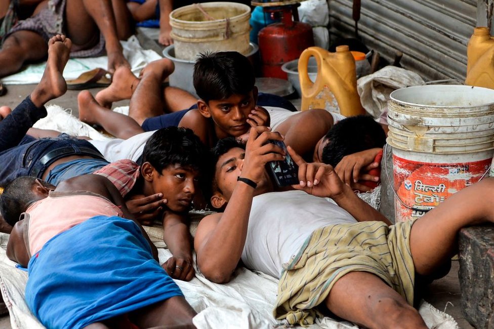 Индийские рабочие смотрят фильм на мобильном телефоне в старых кварталах Нью-Дели 14 июля 2019 года.