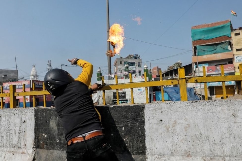 Мужчина, поддерживающий новый закон о гражданстве, бросает бомбу с бензином в мусульманский храм во время столкновения с противниками закона в Нью-Дели, Индия, 24 февраля 2020 г.