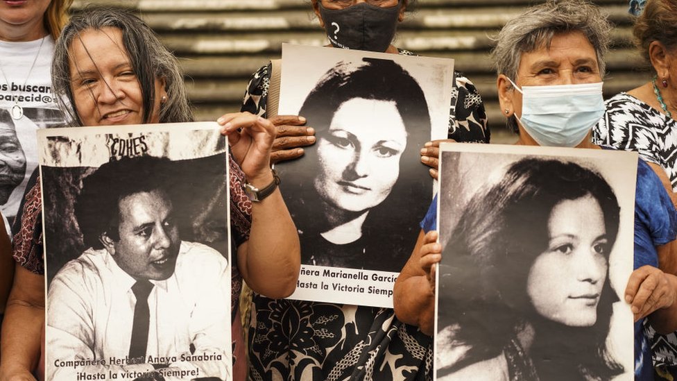 Mujeres sostienen imágenes de víctimas desaparecidas durante la guerra salvadoreña.
