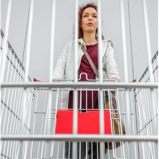 Женщина просматривает решетку пустой тележки для покупок