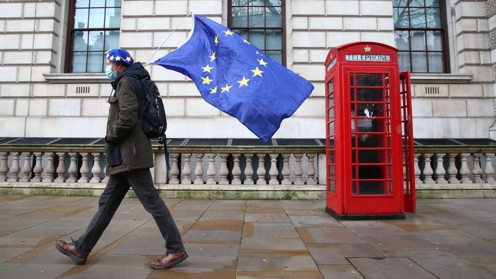 Человек с флагом ЕС проходит мимо красной телефонной будки