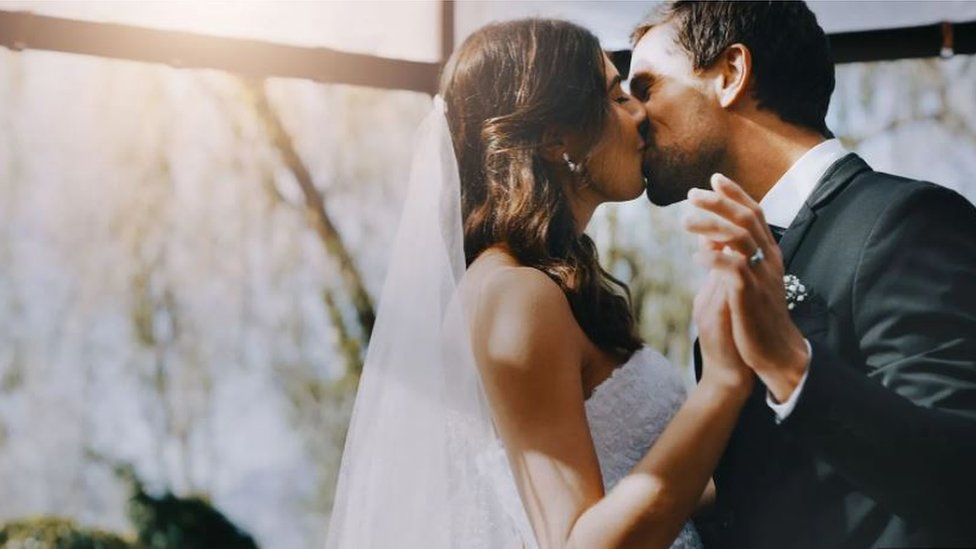 A couple in wedding dress and suit kissing