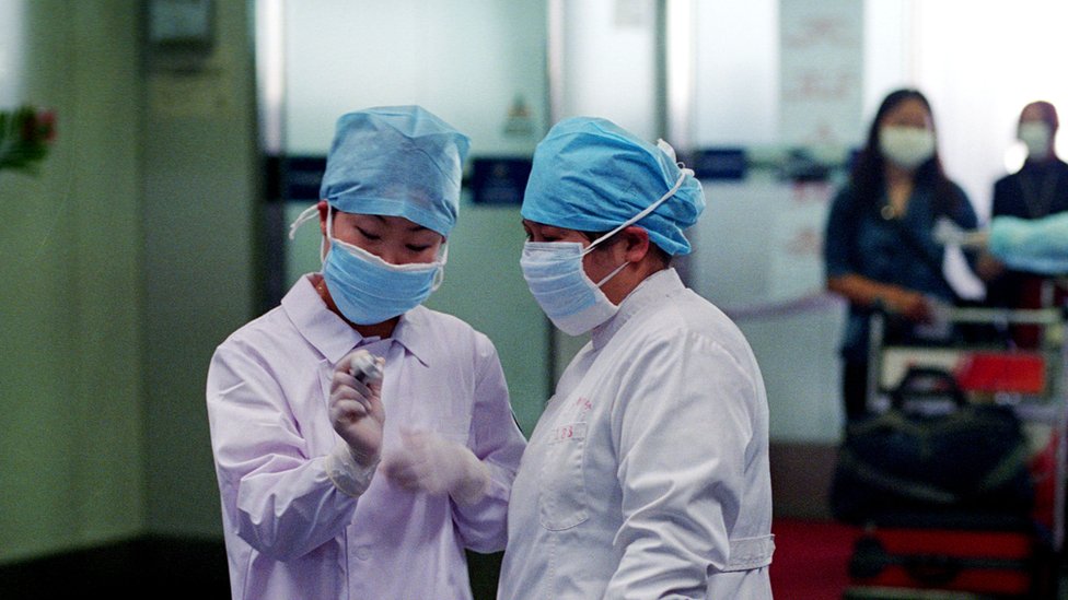 Nurses check a thermometer reading in the departure hall of the Beijing's Capital Airport April 28, 2003