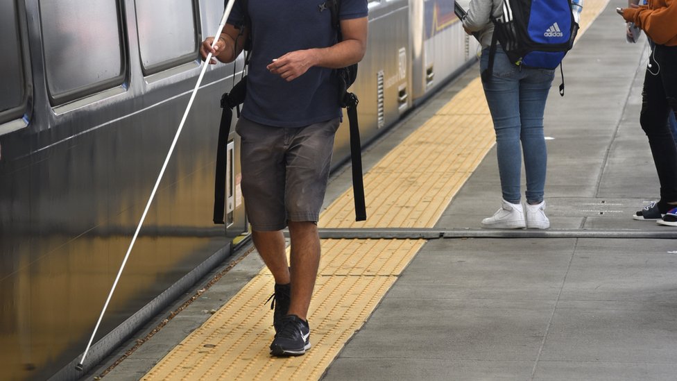 Слабовидящий человек с палкой рядом с поездом