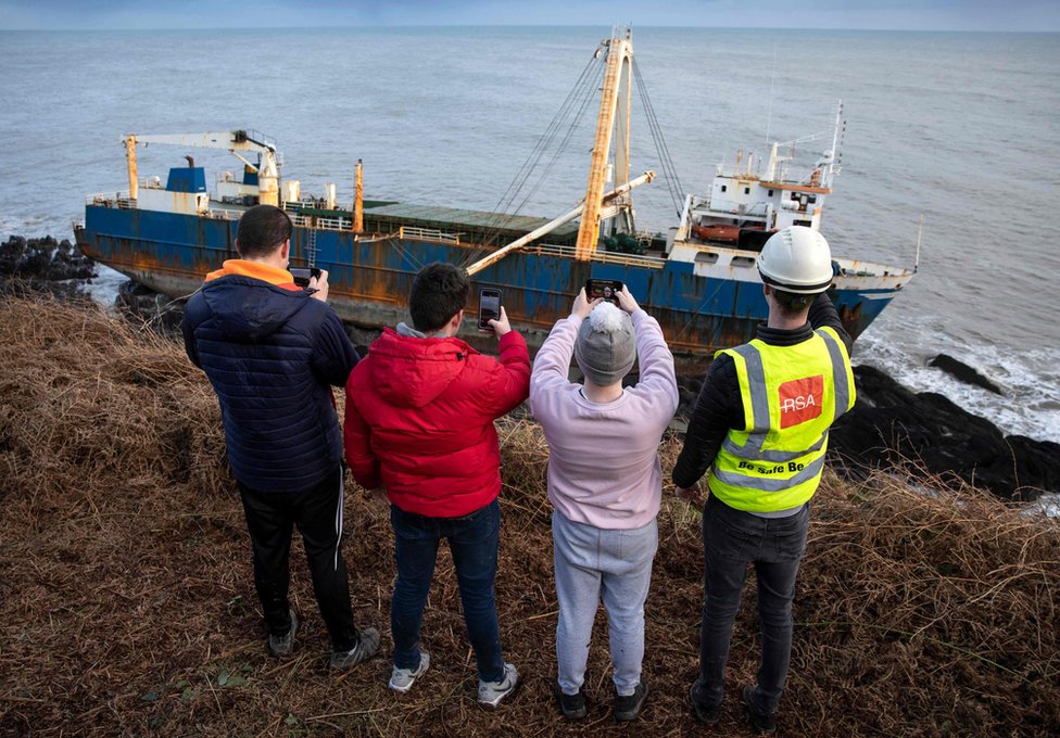People stand and take photos of the abandoned ghost ship Alta