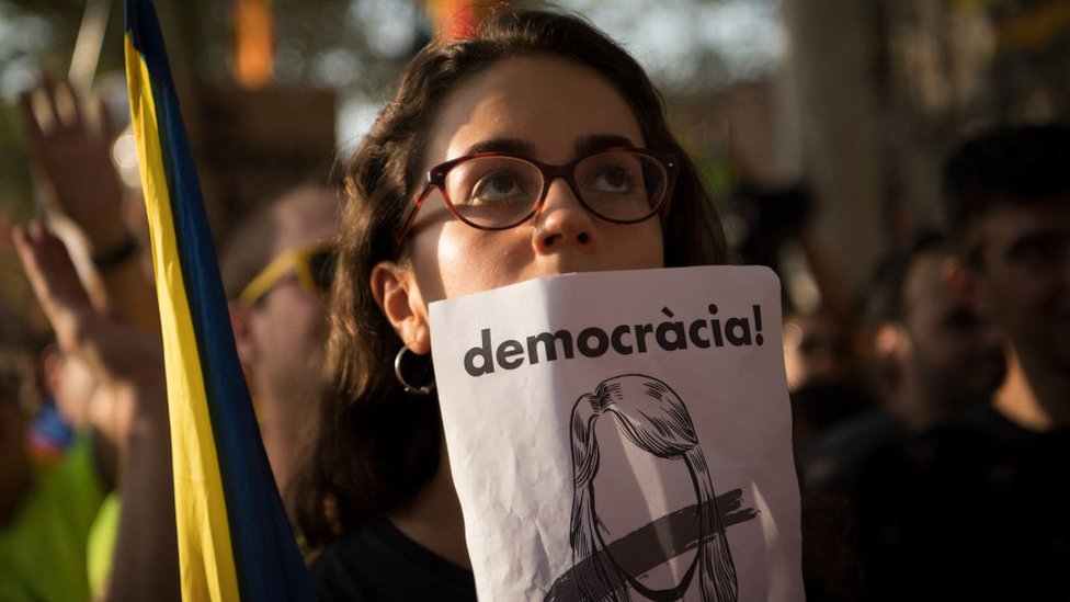 La crisis catalana ha provocado tensiones dentro de la sociedad catalana. Mujer con cartel pidiendo democracia en Cataluña.