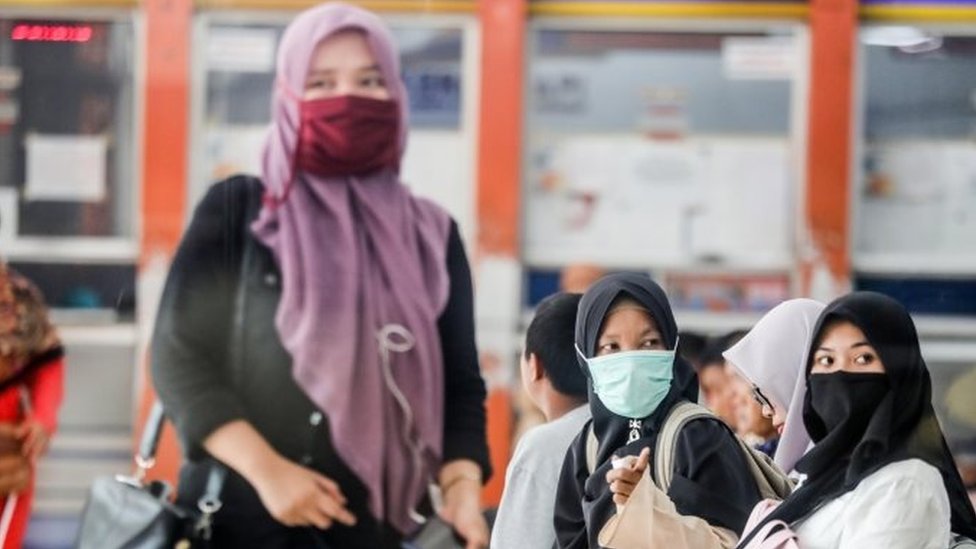 Warga di stasiun kereta Medan, Sumatra Utara, mengenakan masker.