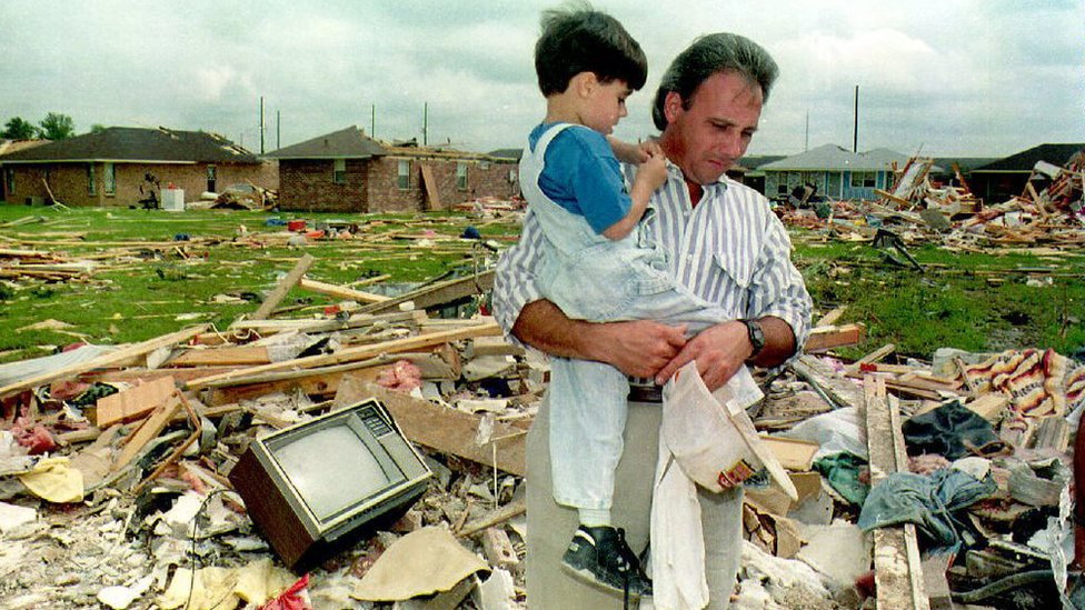 Carlos Cabrera sostiene a su hijo de 4 años, Adrian, entre los escombros que quedan de su casa el 28 de agosto de 1992 después de que el paso del huracán Andrew generara un tornado el 26 de agosto que destruyó su casa y mató a su padre.