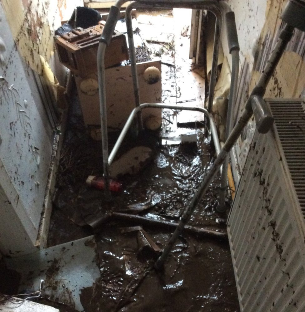 После наводнения в холле Пола Томаса остались грязь и мусор