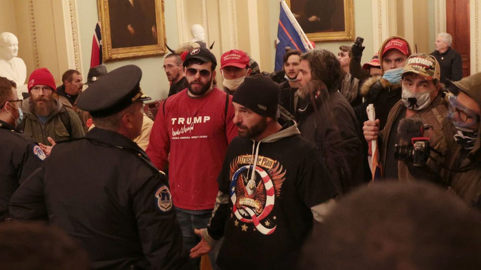 A protester wearing a Q shirt talks to police inside the US Capitol building on Wednesday