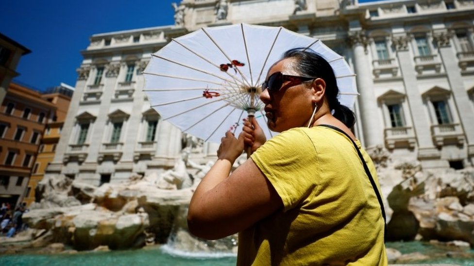Žena drži suncobran dok pozira kod fontane di Trevi