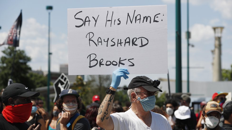 Seorang demonstran mengangkat papan bertulisan nama Rayshard Brooks di Atlanta.