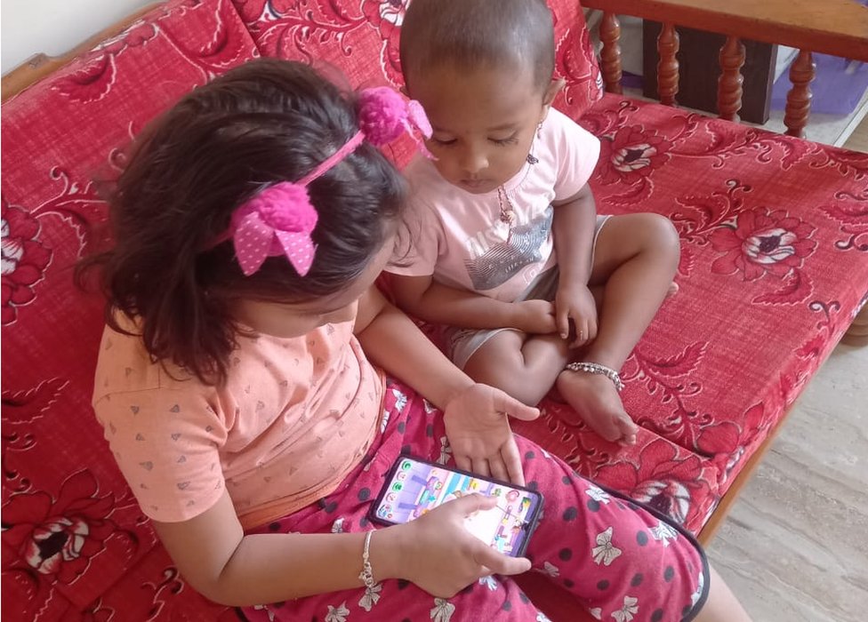Dos niñas juegan con un teléfono.