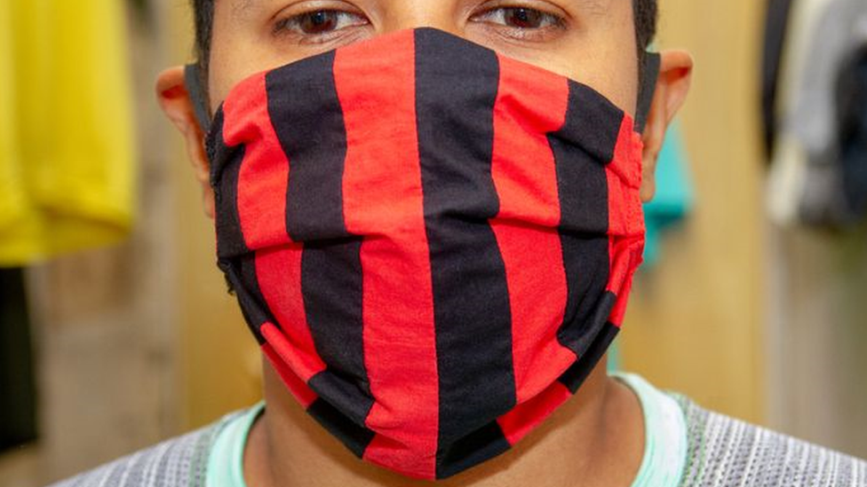 Foto do rosto de um homem, que usa uma máscara vermelha e preta