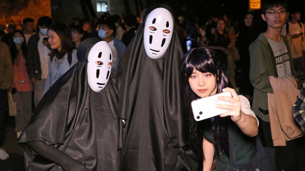 上海街頭一位女子用手機與作妖魔鬼怪打扮的遊客合照（31/10/2023）