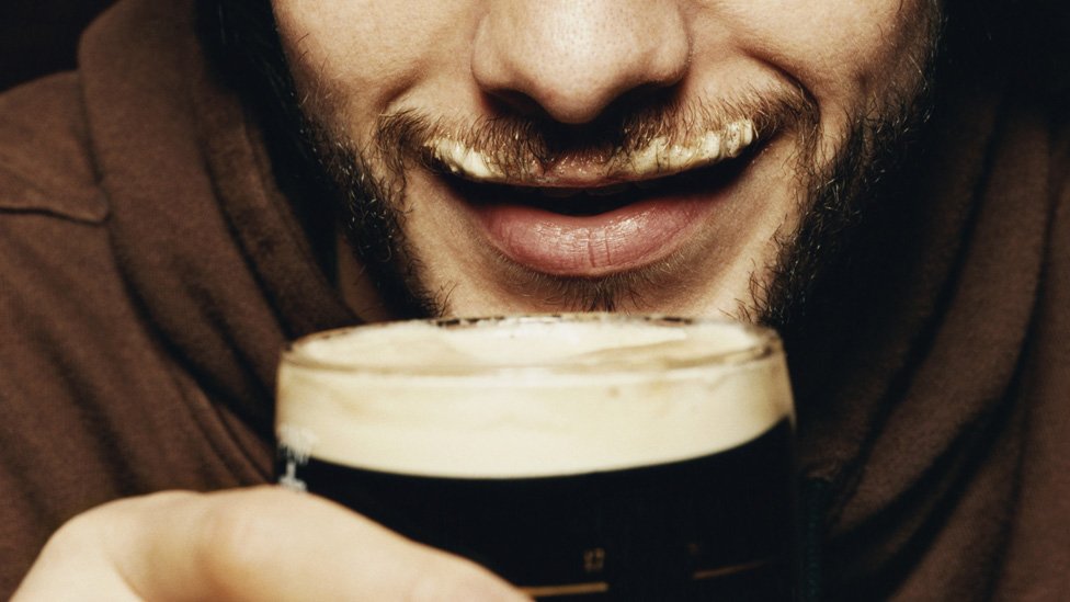 Мужчина пьет пинту пива Guinness