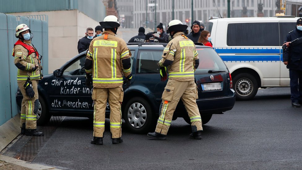 Пожарные работают возле автомобиля, который врезался в ворота главного входа в канцелярию в Берлине