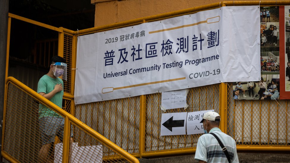 一名戴著透明面罩與口罩的年輕男子（左）走出香港某新冠病毒普及社區檢測計劃採樣中心（1/9/2020）