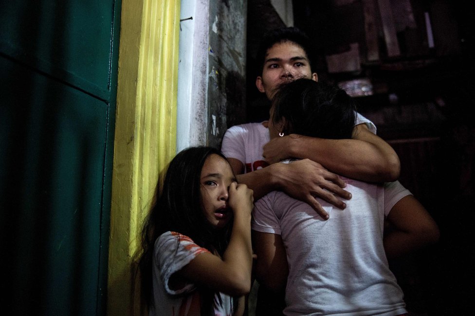 На этом снимке, сделанном 5 января 2017 года, видно, как родственники плачут, когда коронеры уносят тело предполагаемого наркодилера, убитого во время операции по задержанию закупок наркотиков в Маниле