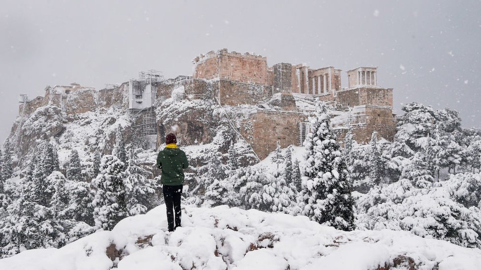 A man takes photos of The Parthenon temple atop the Acropolis hill archaeological site