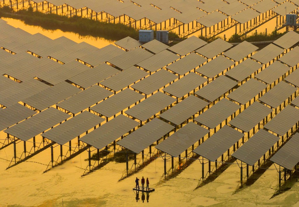 عمال يتفقدون الألواح الشمسية في محطة لتوليد الطاقة باستخدام تلك الألواح في الصين.