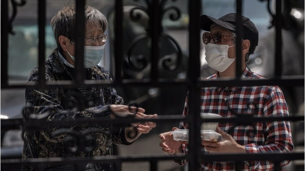 上海的一個被封鎖的住宅區，兩位老人在大門口交談