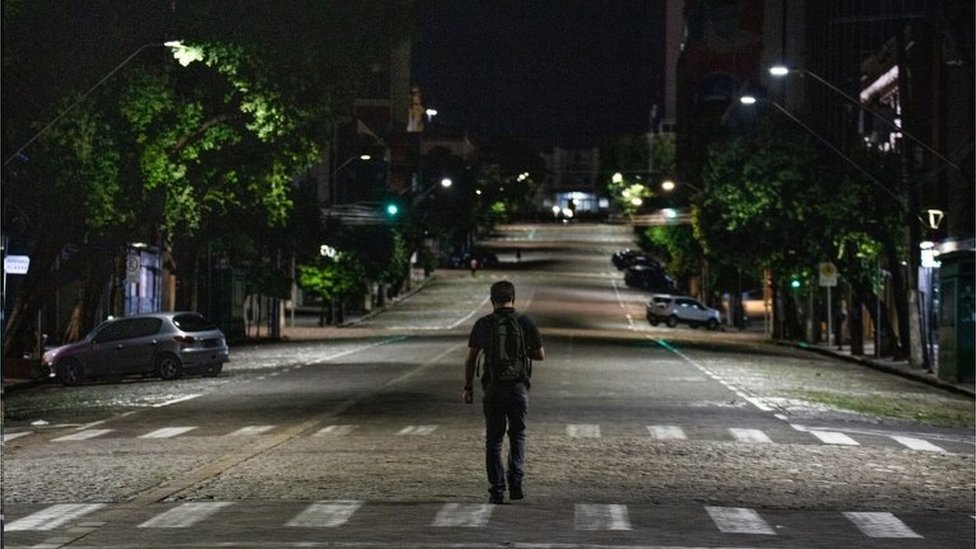 Homem anda em rua vazia à noite