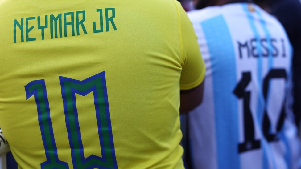 Duas pessoas com as costas das camisas de Neymar e de Messi por suas seleções