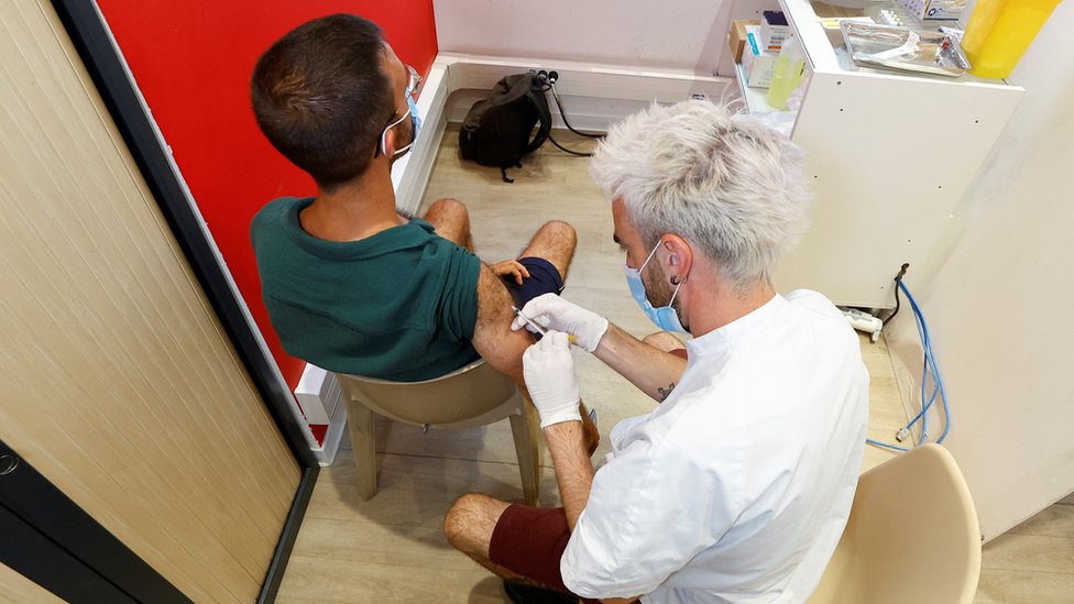 Trabajador de la salud vacunando a un hombre contra la viruela del mono.