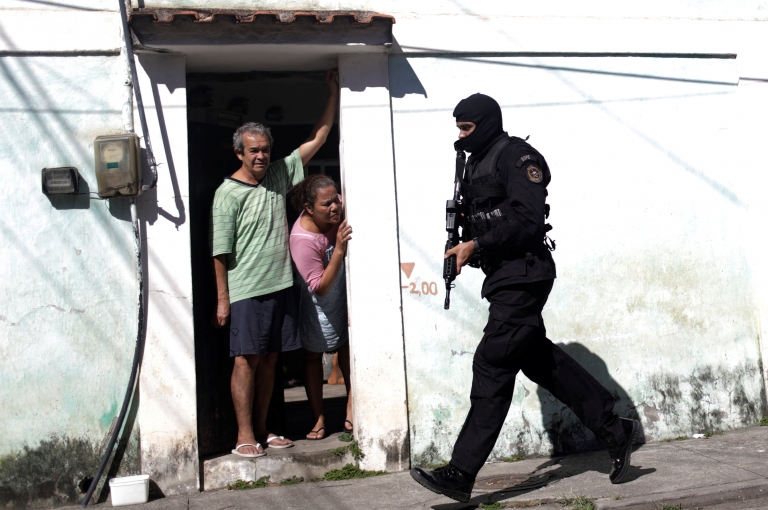 Жители наблюдают, как полицейские патрулируют во время операции против торговцев наркотиками в трущобах Cidade de Deus в Рио-де-Жанейро, Бразилия, 10 июля 2017 г.