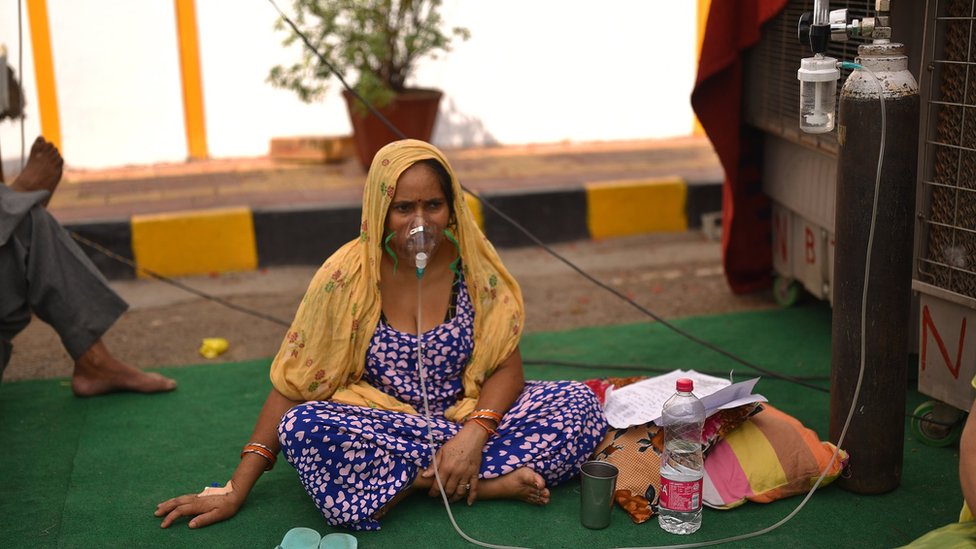 印度新德里一座錫克廟內一位懷疑感染新冠病毒的女士坐在地上吸氧（1/5/2021）