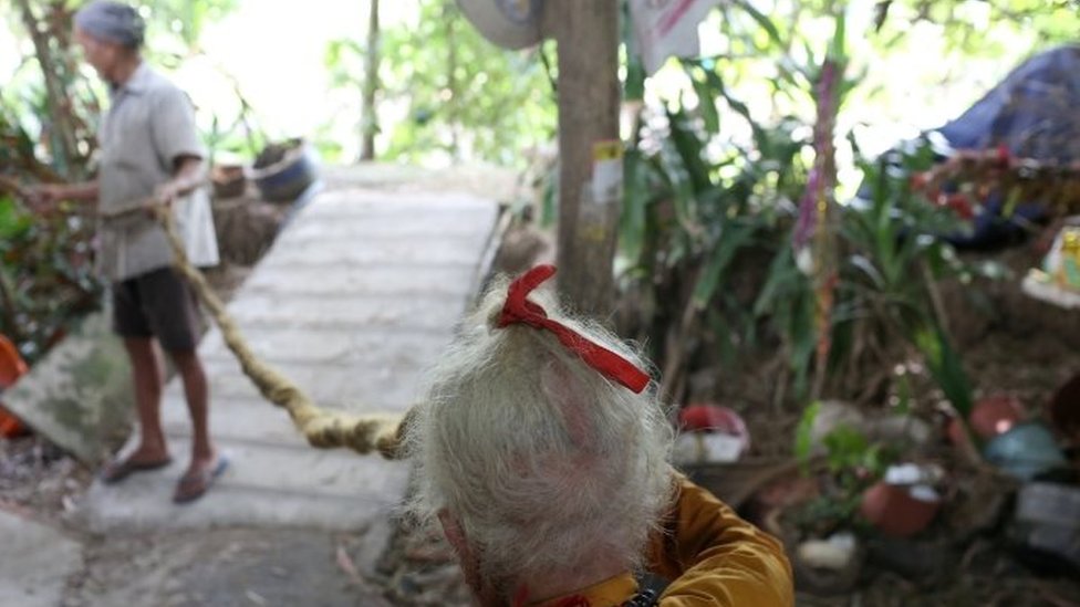Nguyen Van Chien, 92, tahun dengan rambut yang dipegang anaknya.